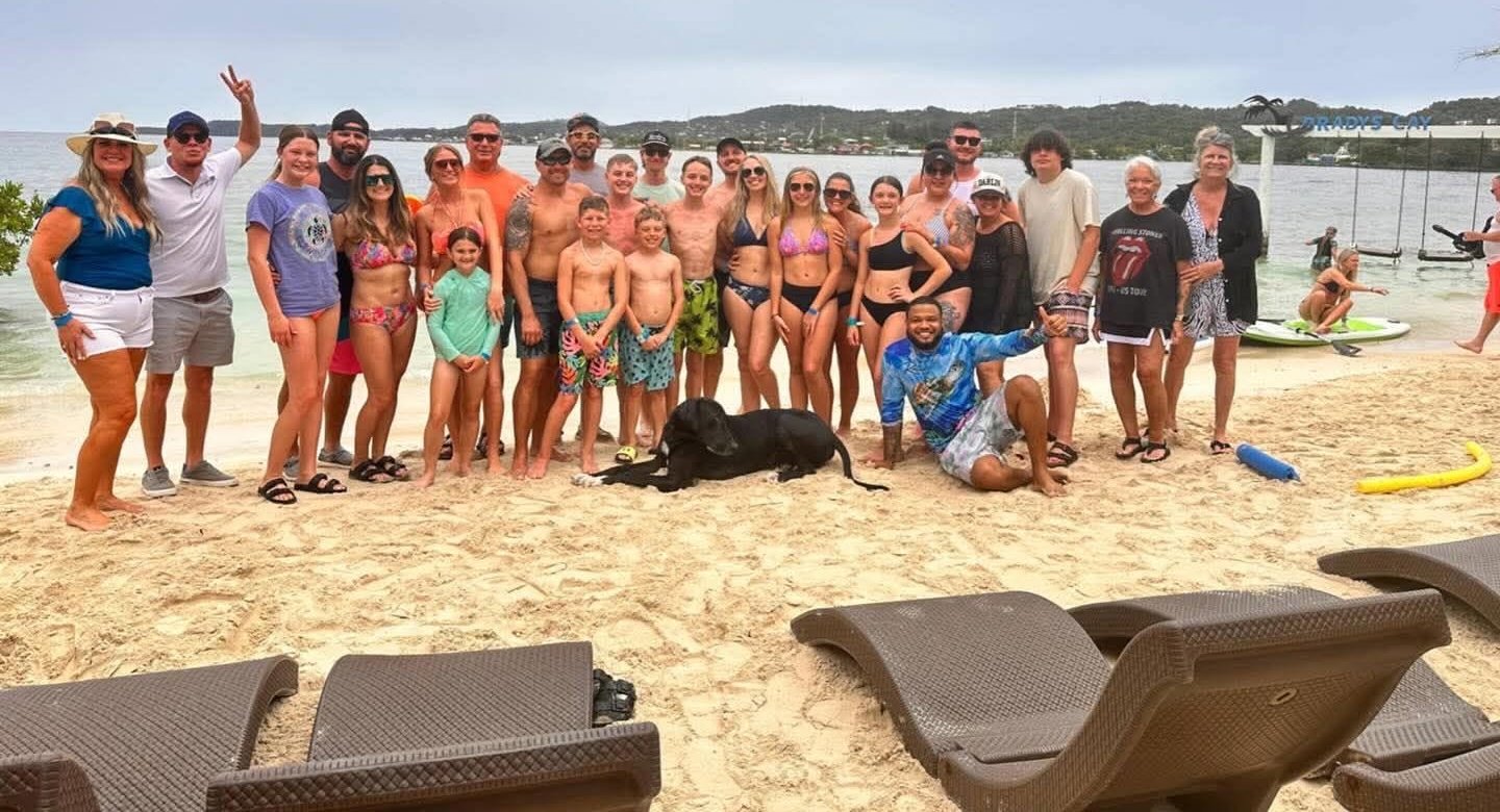 A happy Island Breeze tour group on a white-sand Roatán beach