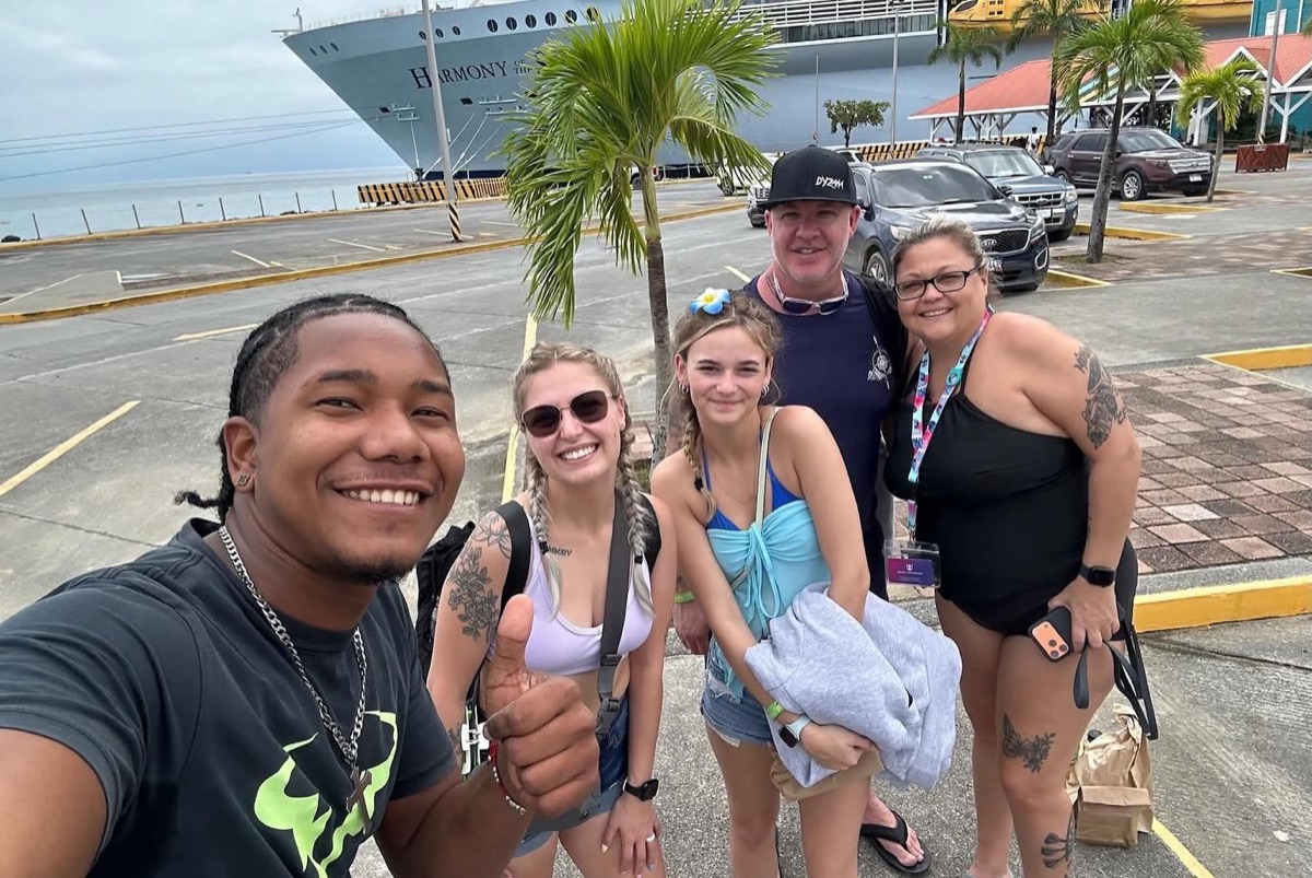 Island Breeze guide with happy guests in front of their cruise ship